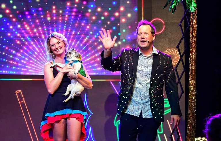 Farrell Dillon and his stage partner with a pug under colorful stage lights