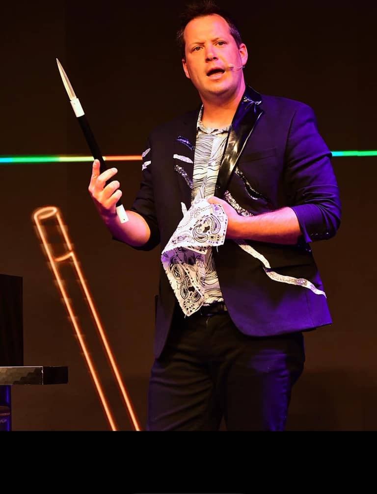 Farrell Dillon in a purple jacket performing a card flourish