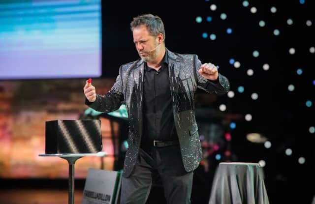 Farrell Dillon performing a card trick under stage lights